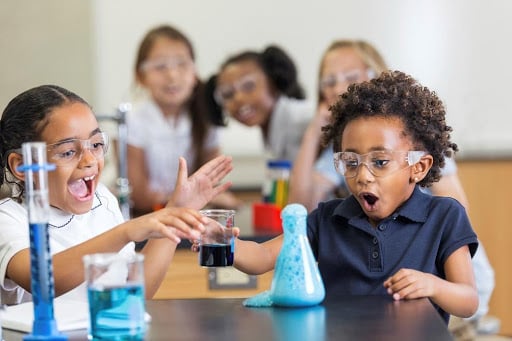 children looking excitedly at beaker overflowing