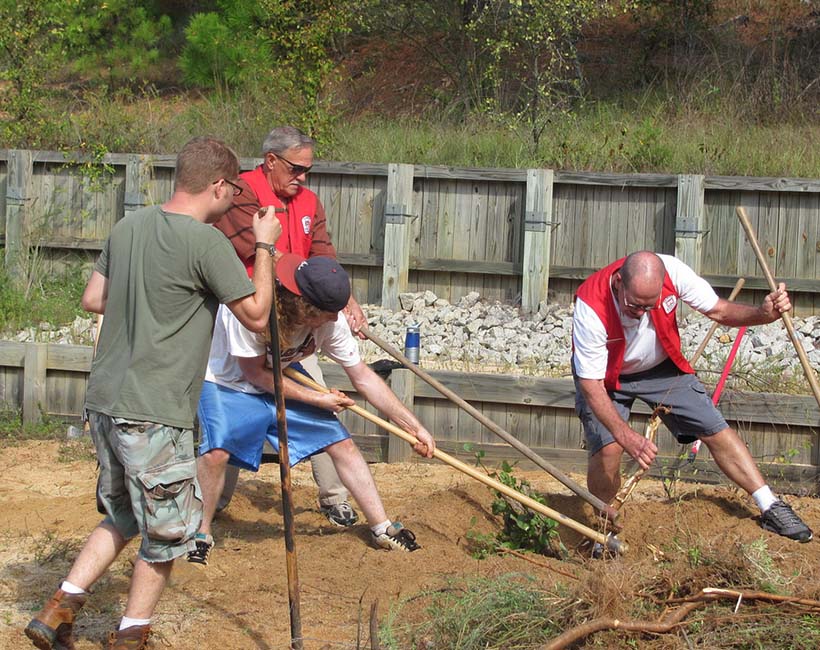 Corporate volunteers digging in dirt field