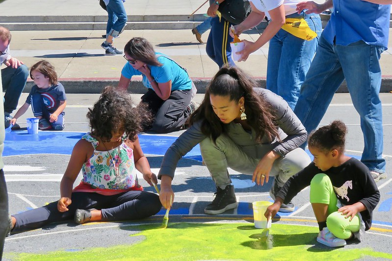 Woman helping children do chalk art on the street